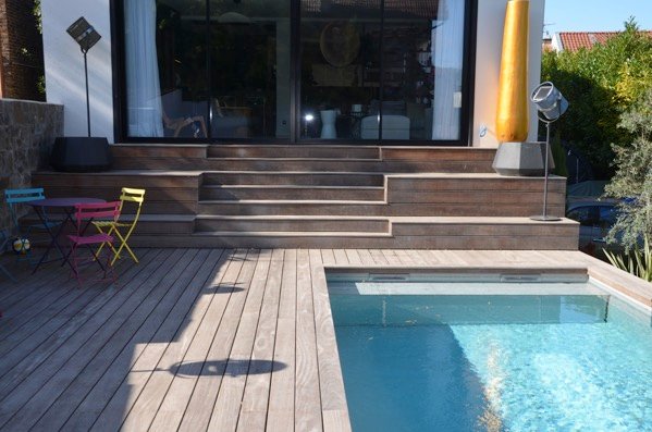 Piscine entourée de terrasse en bois.